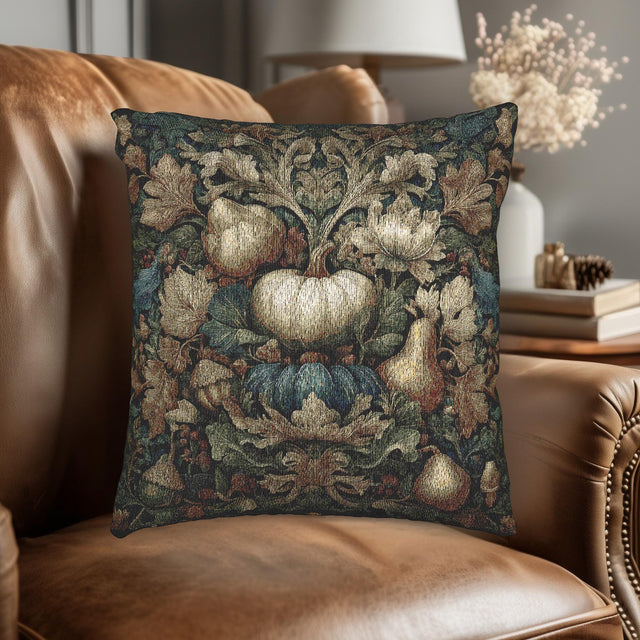 A decorative throw pillow with a floral and autumnal design sits on a brown leather couch in a cozy living room setting.