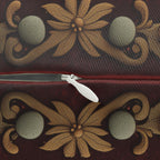 a close-up view of a zipper with a white plastic zipper pull, set against a background with a floral pattern in shades of red and gold.