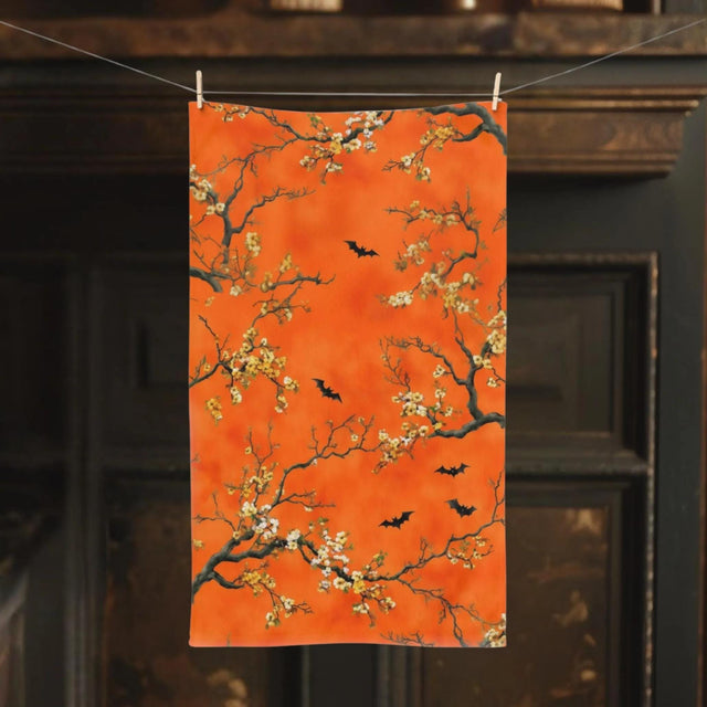 An orange towel with a floral pattern featuring bats and branches hangs from a clothespin.